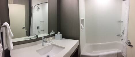 A bathroom with a white sink, mirror, and bathtub.