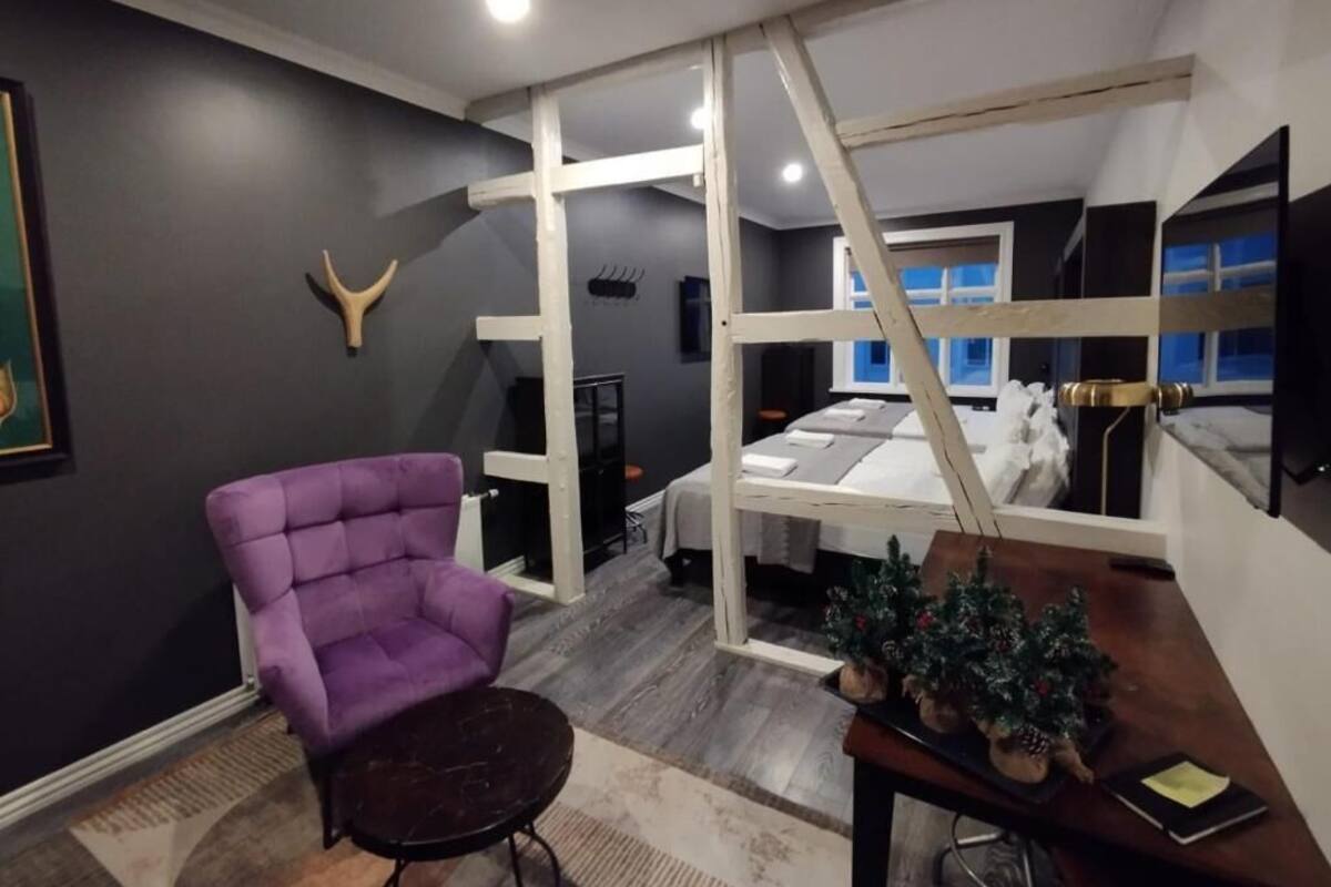 Ein Zimmer mit einem violetten Sessel, einem kleinen Tisch, einem Bett und einem Weihnachtsbaum.