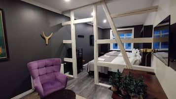 Een kamer met een paarse fauteuil, een tafeltje, een bed en een kerstboom.