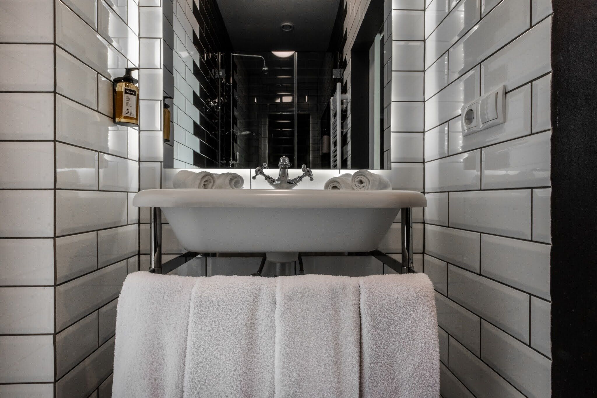 A modern bathroom with a freestanding sink, a towel rack, and a wall-mounted light fixture.
