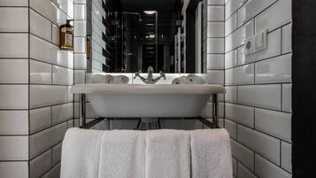 A modern bathroom with a freestanding sink, a towel rack, and a wall-mounted light fixture.