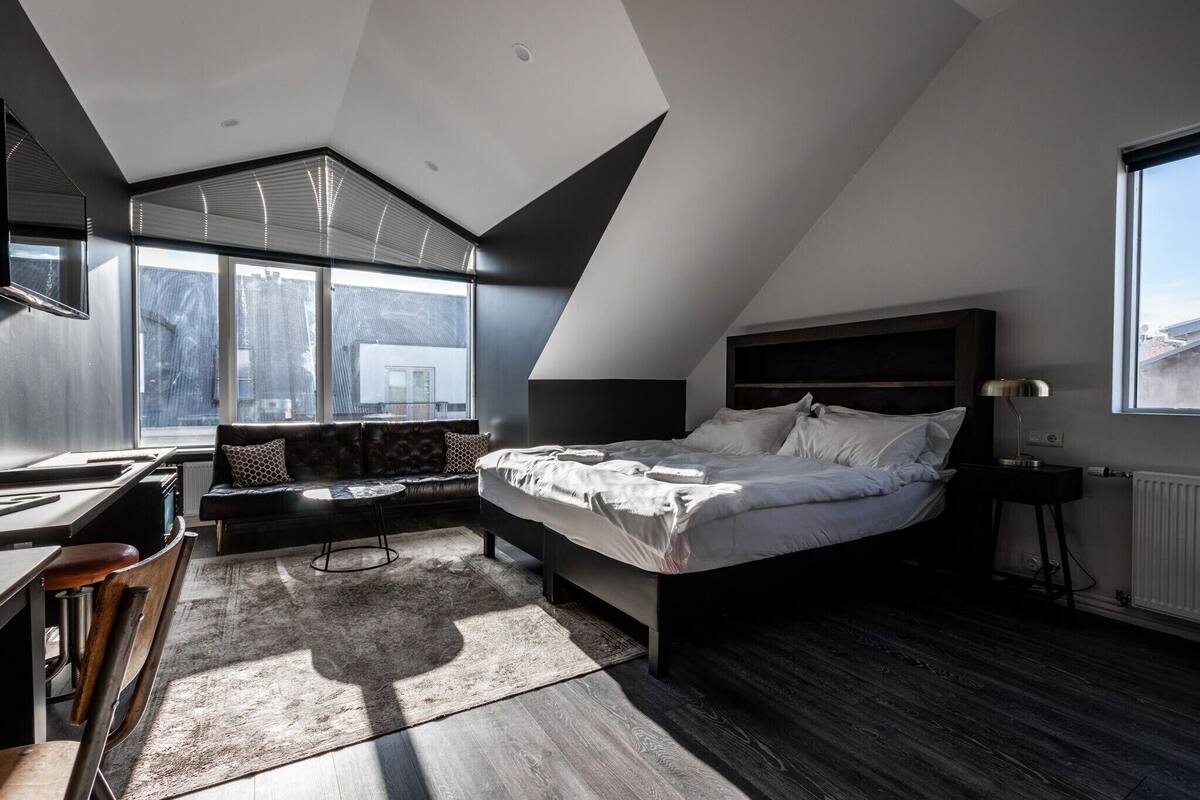 Ein modernes Schlafzimmer mit einer Schlafgalerie, einem großen Bett, einem Schreibtisch und Blick auf die Stadt.