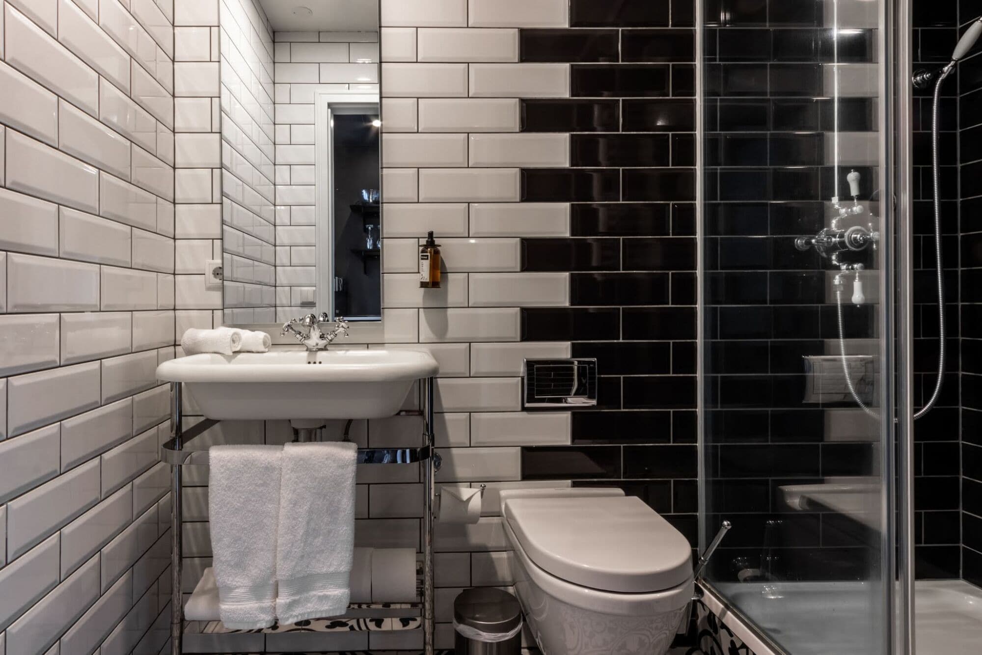 A modern bathroom with a white sink, a toilet, and a glass shower enclosure.