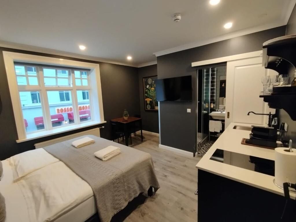Een moderne hotelkamer met een bed, een bureau, een badkamer en uitzicht op een gebouw.