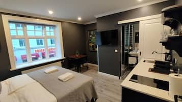 Een moderne hotelkamer met een bed, een bureau, een badkamer en uitzicht op een gebouw.