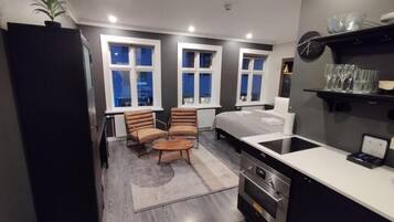 A compact kitchen with a stove, sink, and a small dining area with a chair and table.