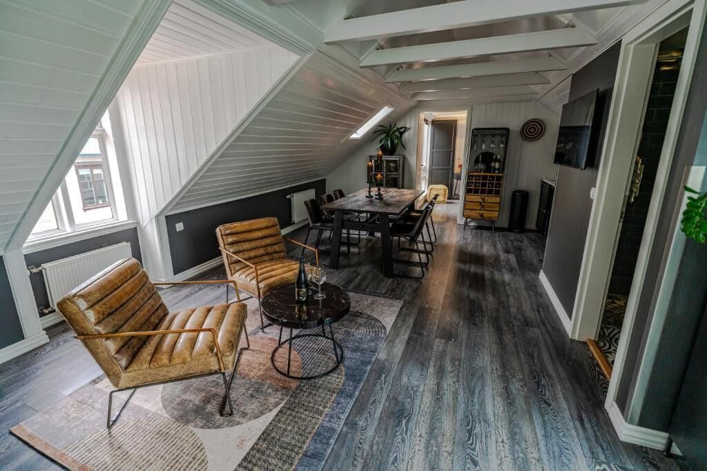 A loft-style room with a dining table, chairs, a sofa, and a fireplace.