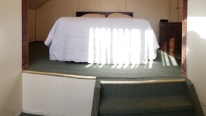 Ein Schlafzimmer mit einem Bett, einem hölzernen Kopfteil, einem Nachttisch und einer Wanduhr.