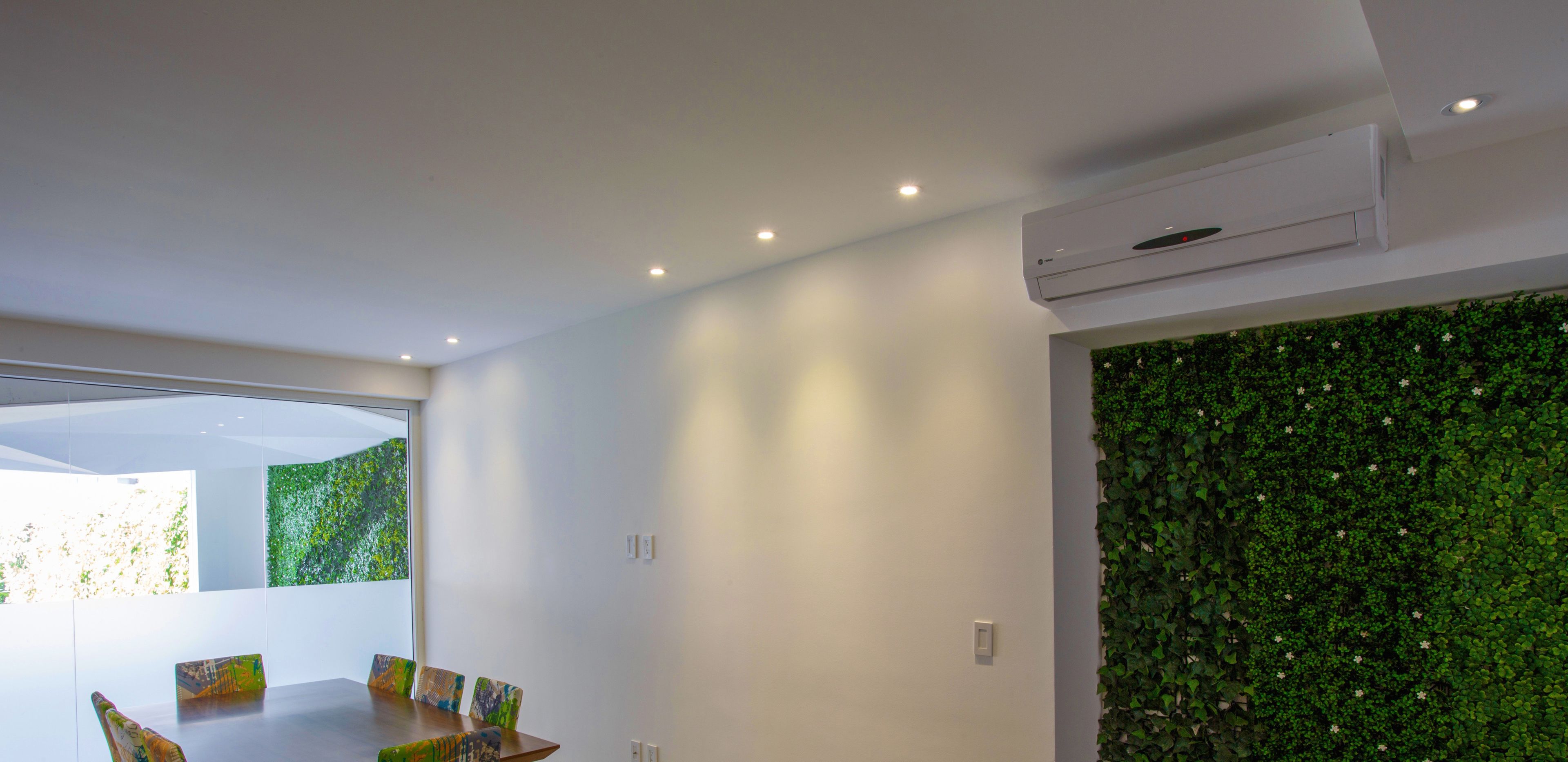 Un intérieur moderne comprenant un coin repas, des spots encastrés au plafond et un climatiseur fixé au mur.