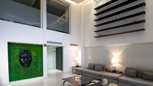 Una sala moderna con un sofá gris, una mesa de centro y un panel decorativo verde.