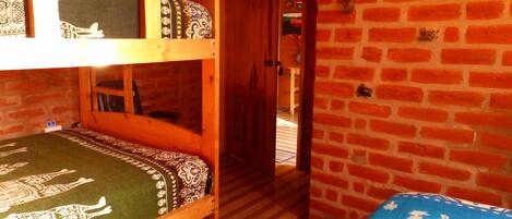A room with a bunk bed, a wooden door, and a brick wall.