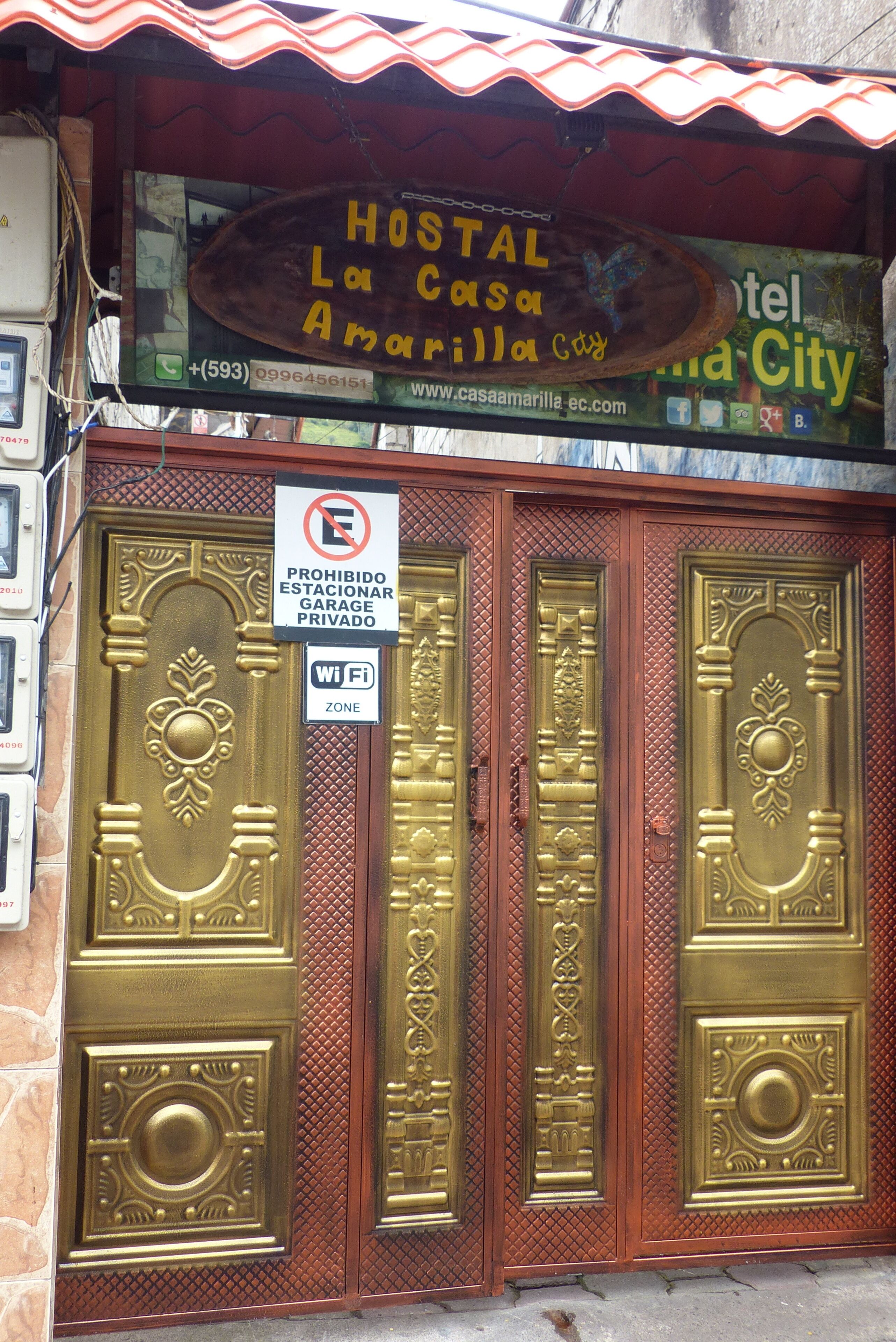 A hotel entrance with ornate golden doors, a sign prohibiting parking, and a WiFi zone sign.