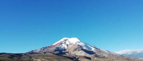 A mountain with a snow-capped peak and a clear blue sky.