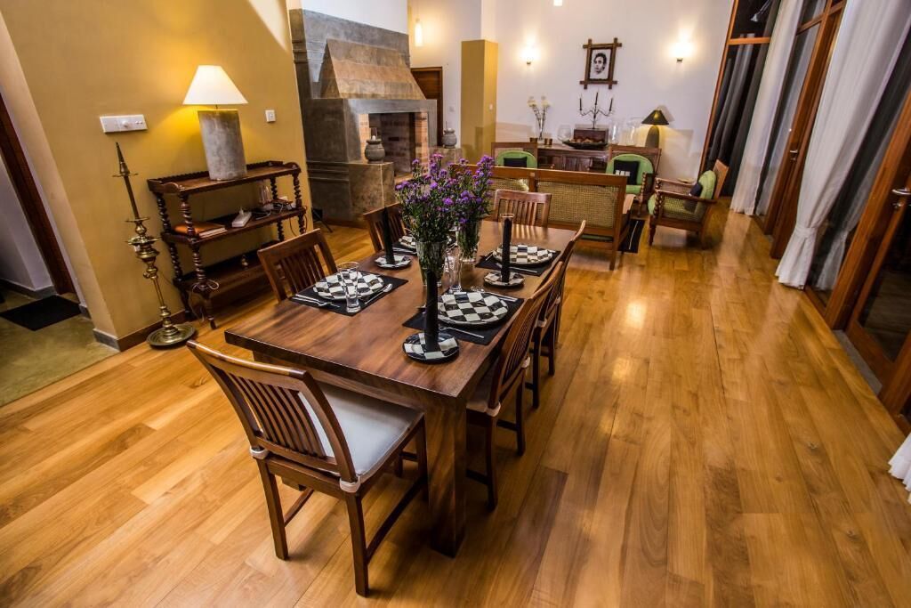 A dining area with a wooden table set for four, surrounded by chairs. A chessboard is placed on the table.