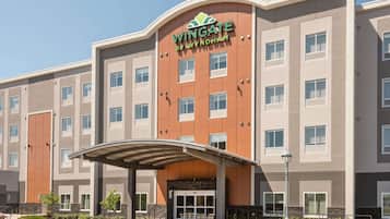 Experience the sleek entrance of The Wingate by Wyndham, marked by a curved overhang and a grid-patterned facade.