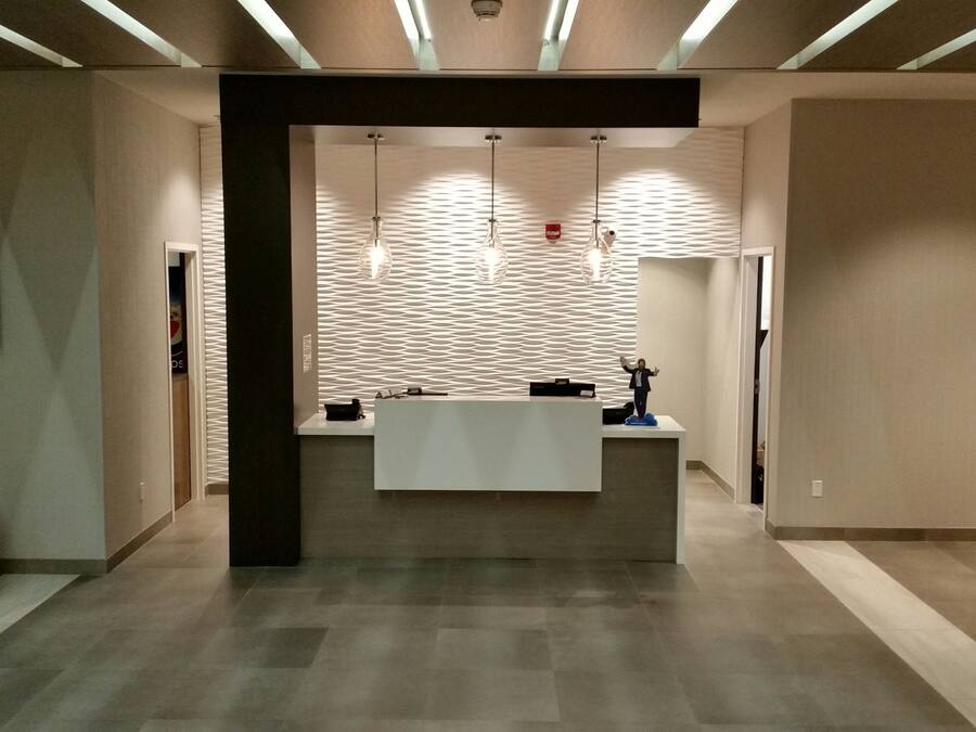 Een receptiezone met een receptiebalie, een wandgemonteerde flatscreen-tv en een gestructureerd wandontwerp.
