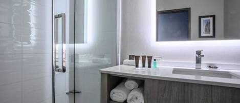 A modern bathroom with a glass shower enclosure, a wooden vanity with a sink, and a mirror above the vanity.