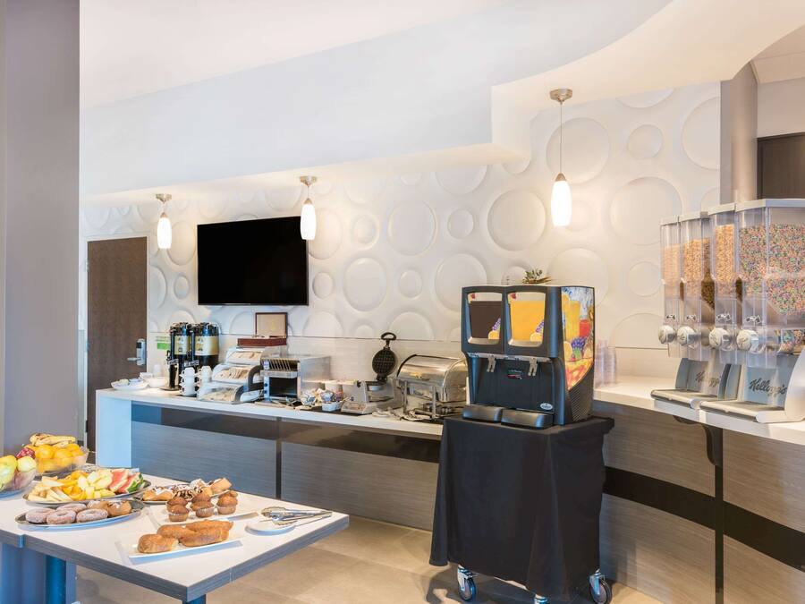 Ein Frühstücksbuffet mit verschiedenen Speisen, einer Kaffeemaschine und einem Saftspender.