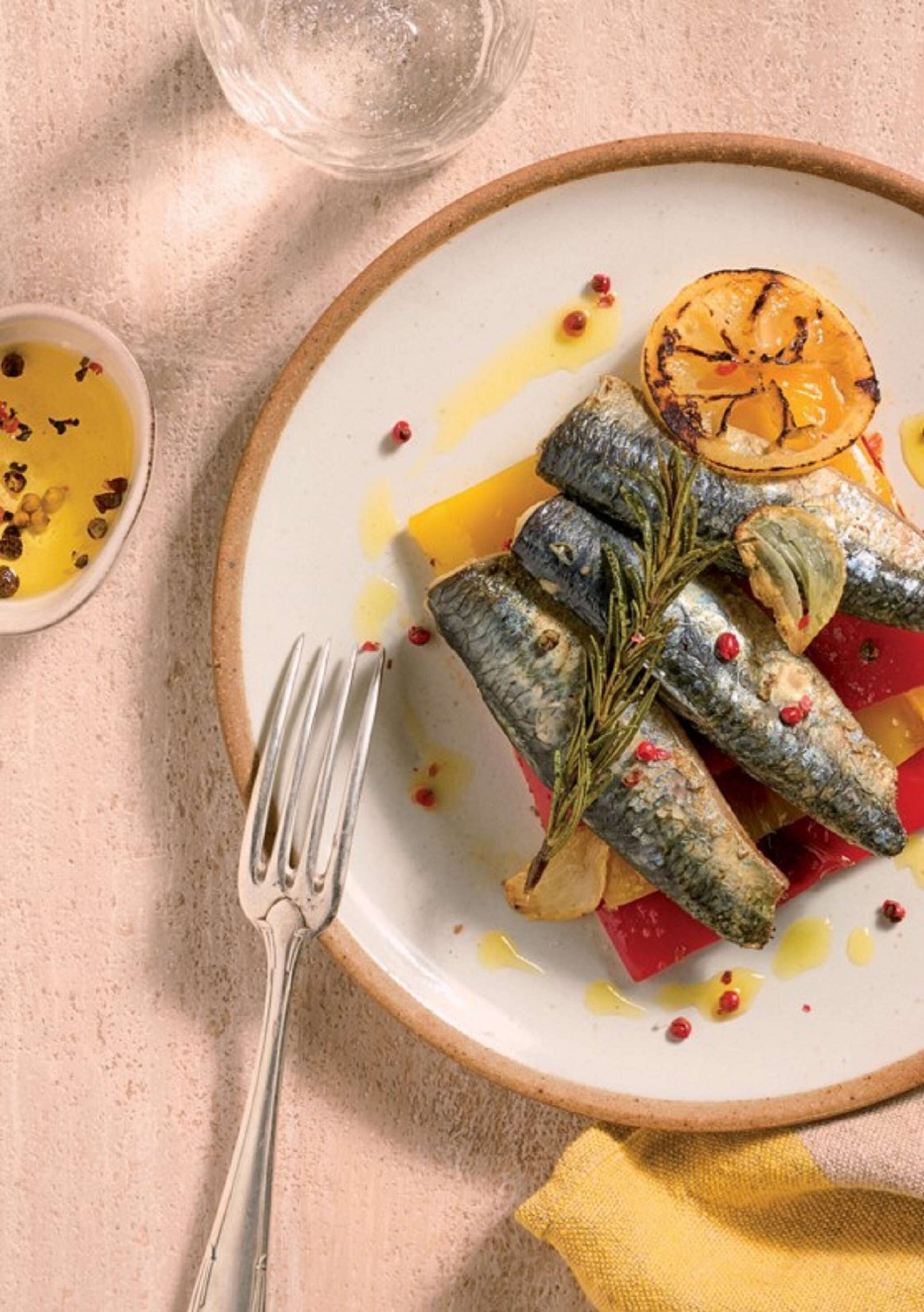 A plate with grilled fish, vegetables, and a garnish of rosemary.