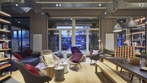 A modern interior with a sofa, armchairs, a coffee table, and a bar area. - Campanile PRIME - Paris Saclay (Gif-sur-Yvette)