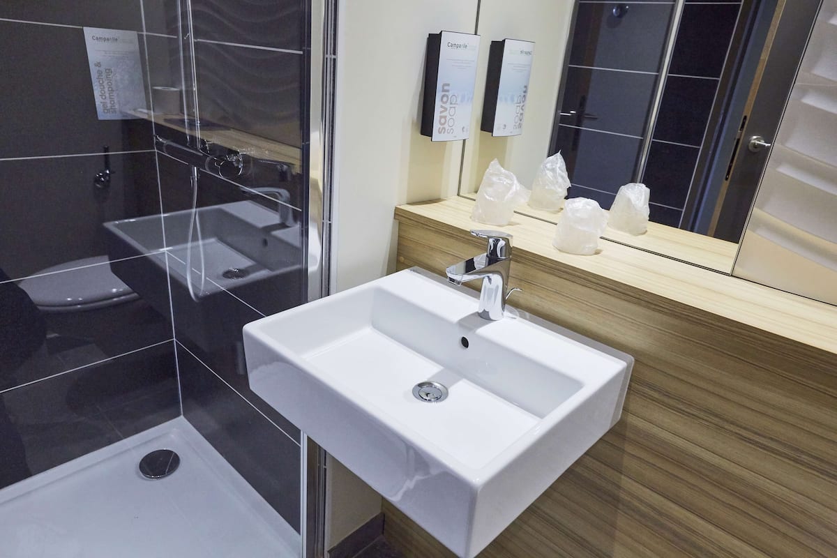 Une salle de bain moderne avec un lavabo blanc, un miroir et un espace douche.
