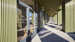 A corridor with a modern design, featuring a bar/lounge area visible through the windows. - Campanile PRIME - Paris Saclay (Gif-sur-Yvette)