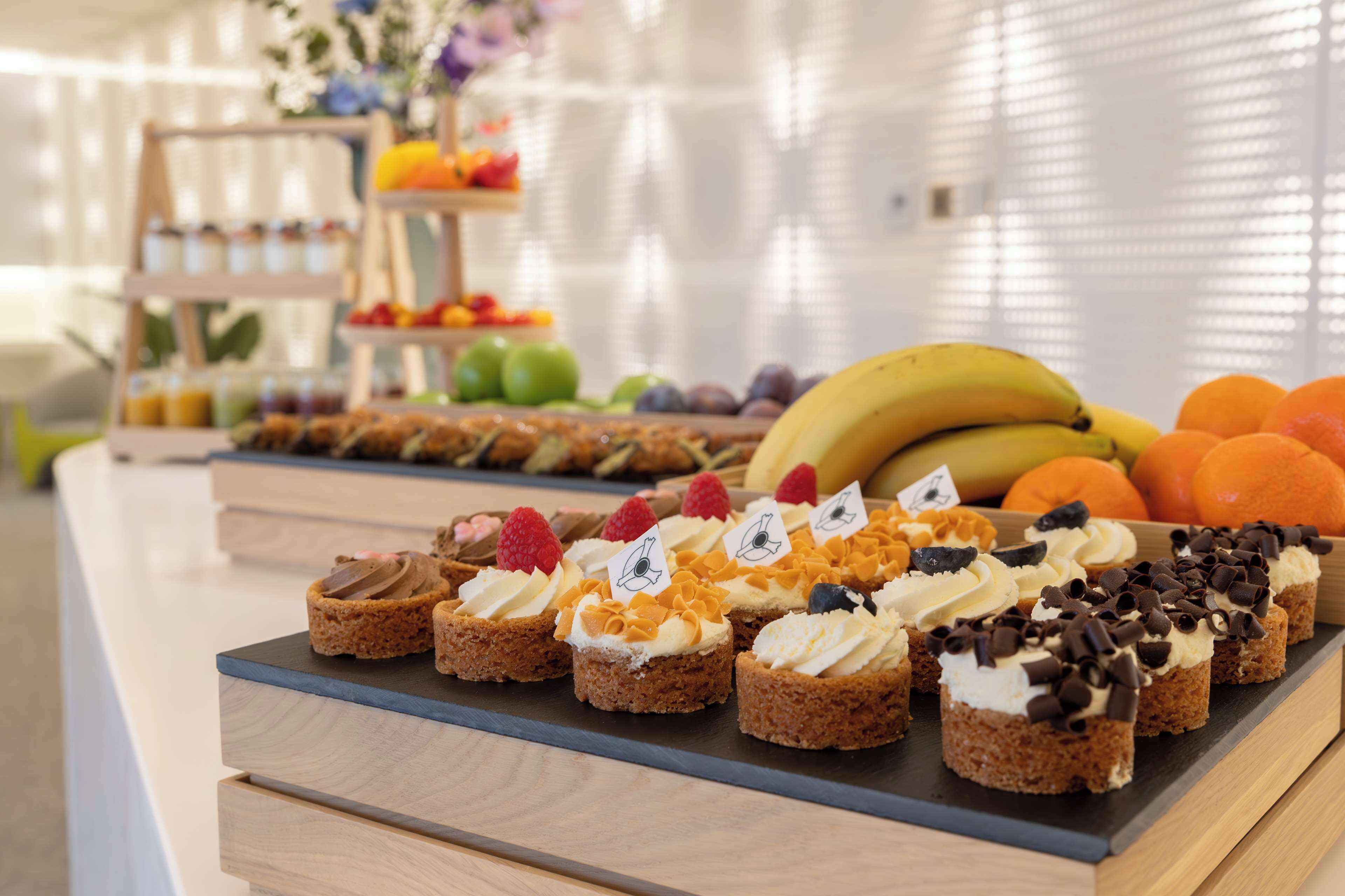 A variety of desserts on a counter with a wooden background and a white wall in the background.