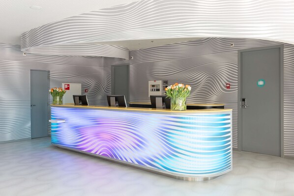 Un mostrador de recepción de diseño moderno, con una pantalla digital y un jarrón de flores.