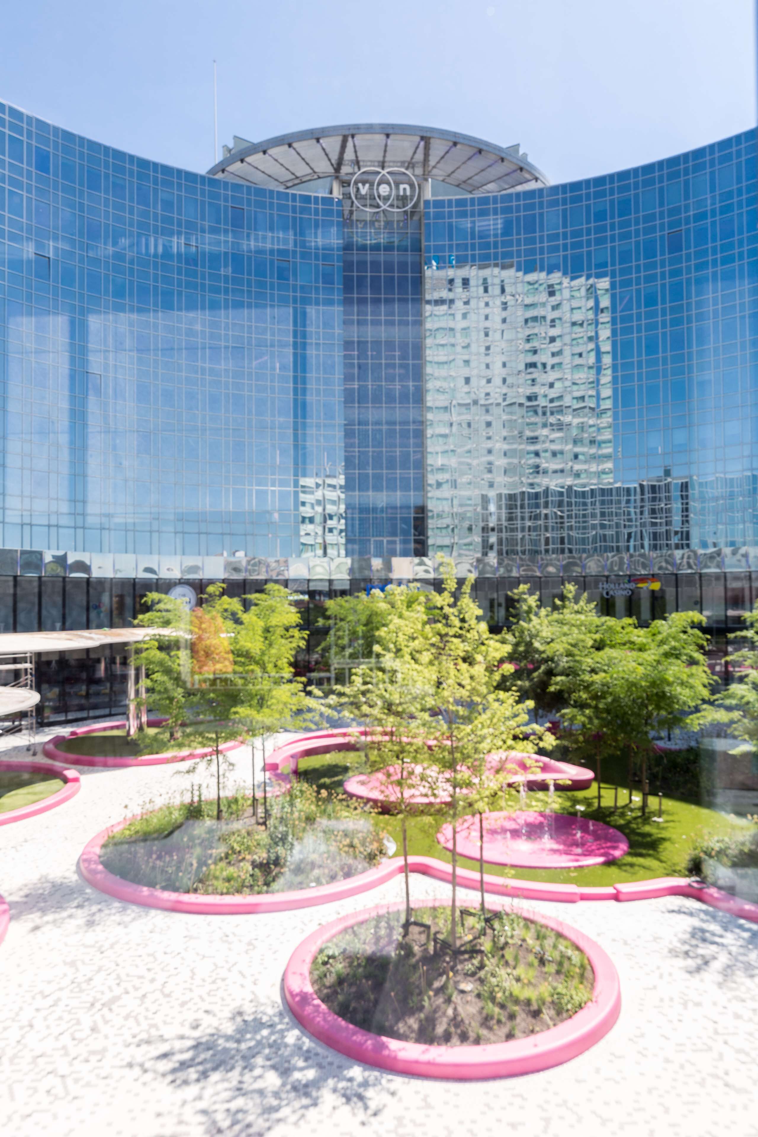 Un bâtiment moderne doté d’une façade en verre incurvée et d’un atrium central.
