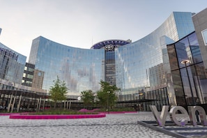 Een modern gebouw met een gebogen glazen gevel en het woord 'Ven' zichtbaar op de grond.