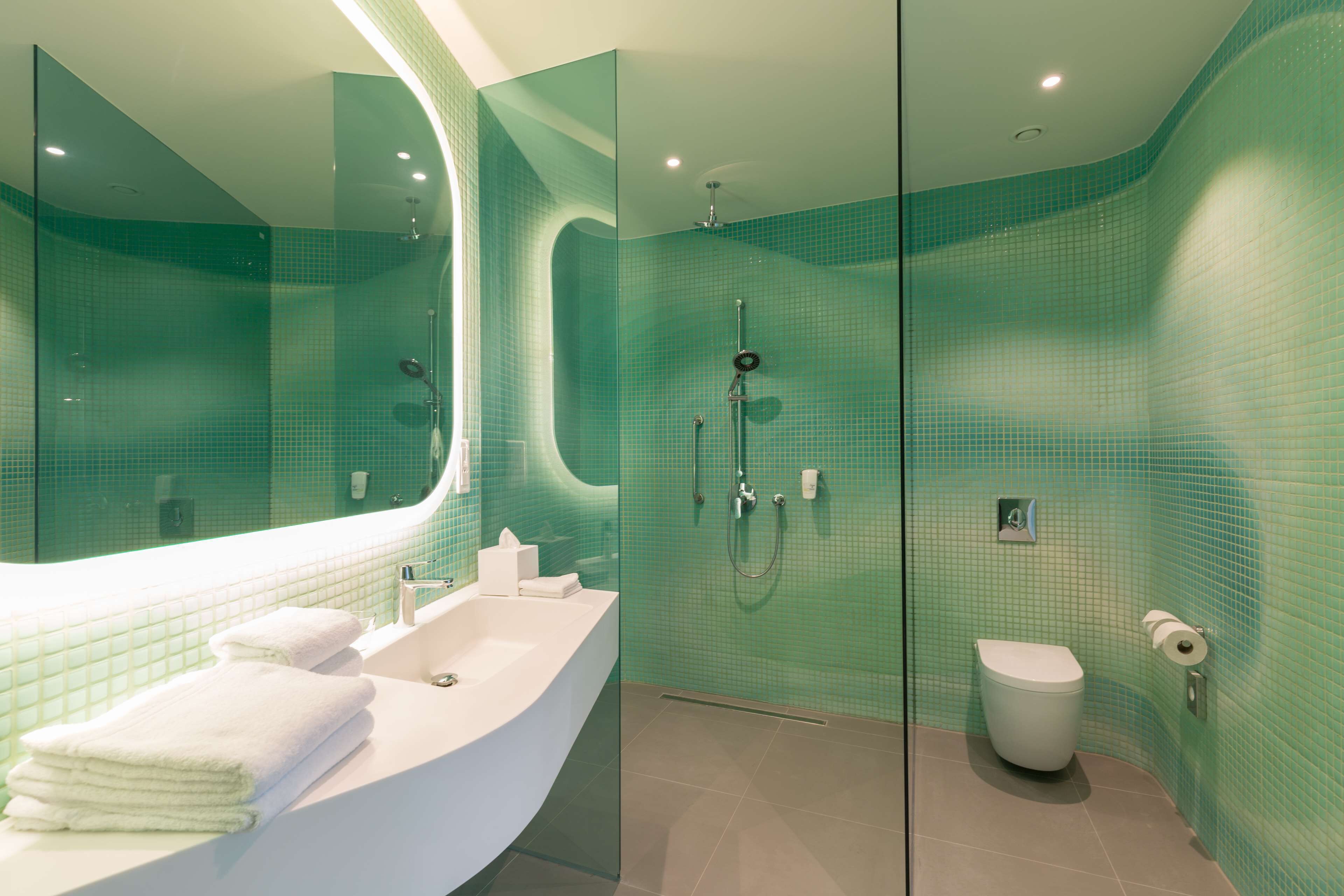 Un baño moderno con cabina de ducha de vidrio, un lavabo blanco y un inodoro.