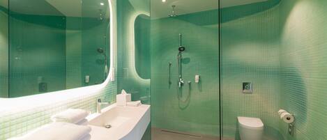 Un baño moderno con cabina de ducha de vidrio, un lavabo blanco y un inodoro.