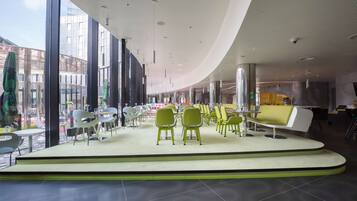 A modern interior with a curved ceiling, seating areas, and large windows.