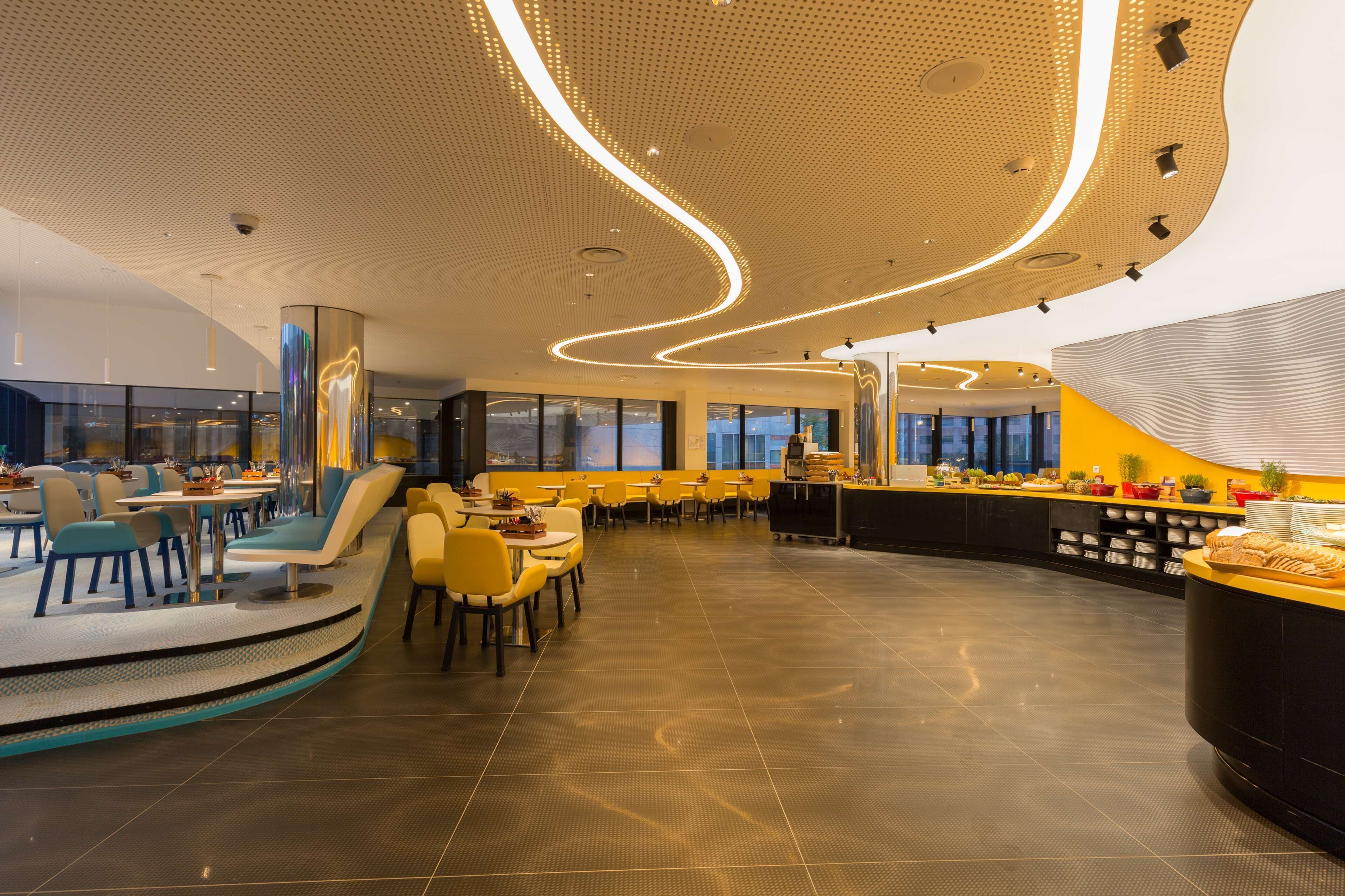 Un espacio interior amplio con una disposición de asientos curva, una barra central y un diseño de techo moderno.