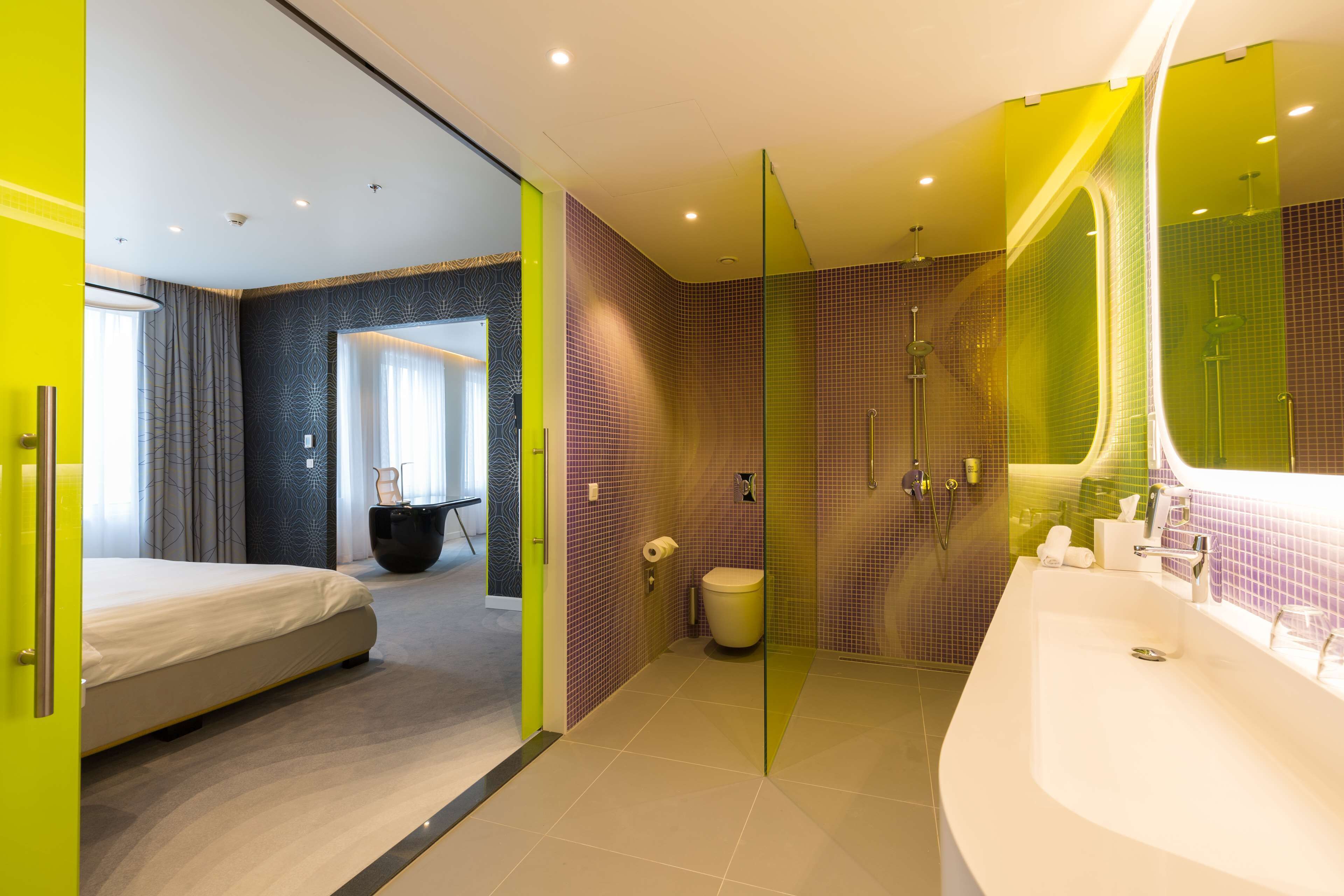 A modern hotel bathroom with a large bathtub, a shower area, and a separate toilet.