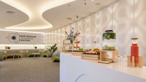 Una moderna zona de recepción con un mostrador blanco, asientos y el logotipo del Centro de Congresos de Ámsterdam.