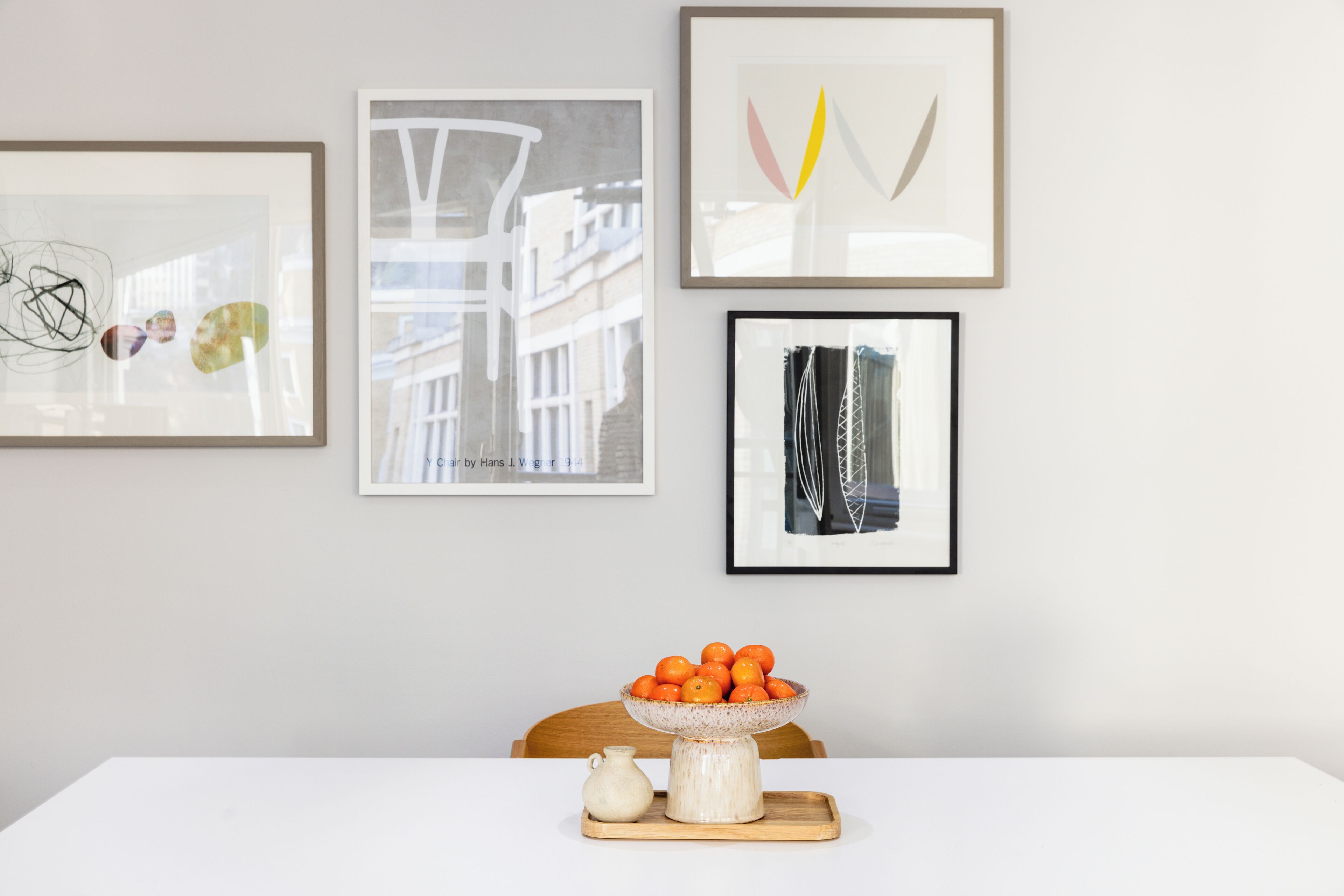 A dining table with a bowl of fruit and a vase.