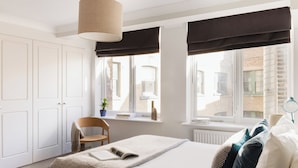 A bedroom with a bed, a chair, a window with curtains, and a radiator. - Native Fenchurch  (London)