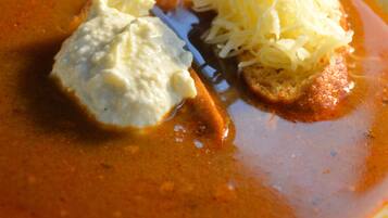 A bowl of soup with a slice of bread and a dollop of cream.