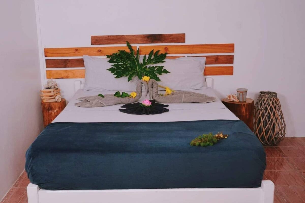 Ein Bett mit Holz-Kopfteil, weißen Kissen und einer dunkelblauen Tagesdecke.