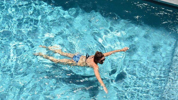 A person swimming in a clear blue pool. - Le Pôle Résidence (Grand-Baie)