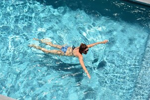 Una piscina al aire libre, sillones reclinables de piscina