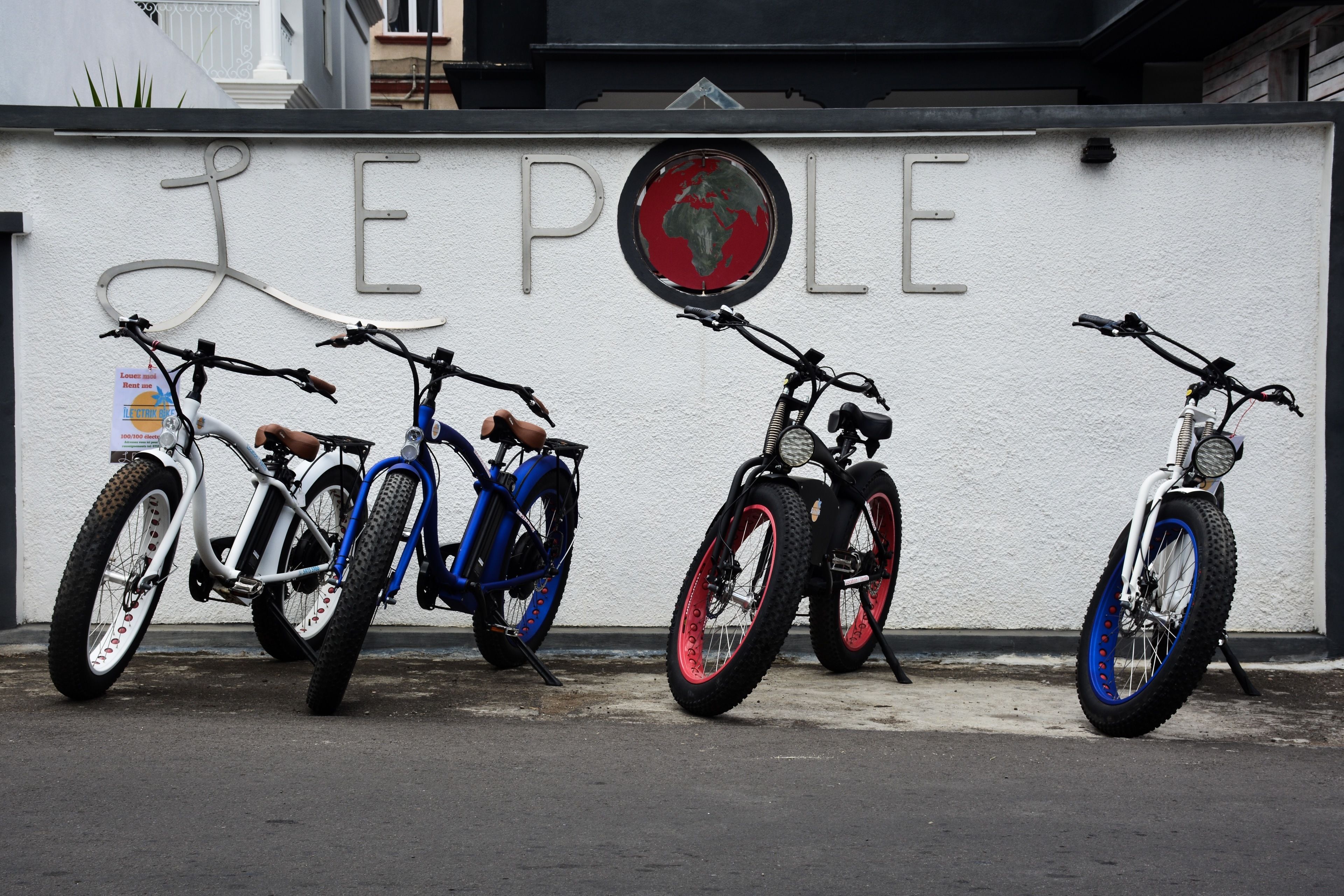 Three bicycles parked against a wall with the word "PEOPLE" and a globe symbol.