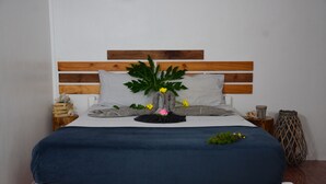 A bed with a wooden headboard, grey pillows, and a blue bedspread. - Le Pôle Résidence (Grand-Baie)