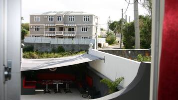 An outdoor seating area with a curved bench and tables, a stone wall, and a view of a multi-story building in the background.