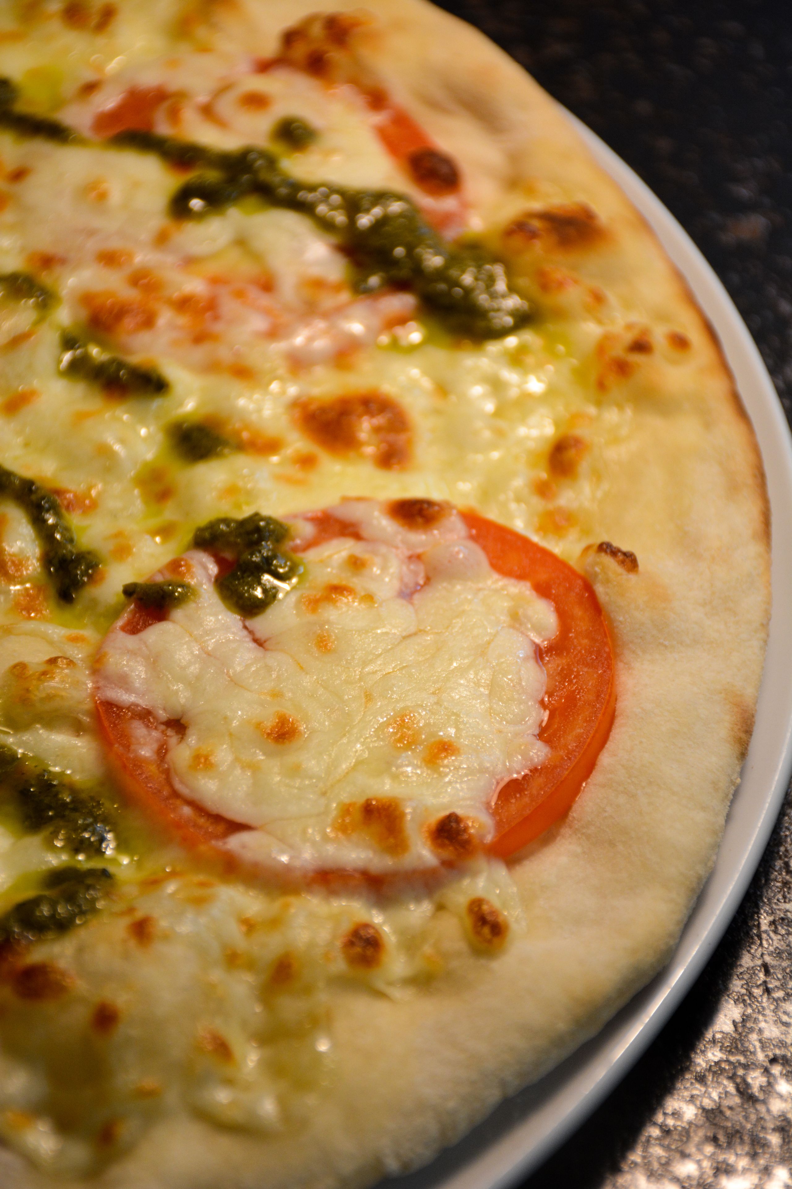 Una pizza con queso y rodajas de tomate sobre un plato.