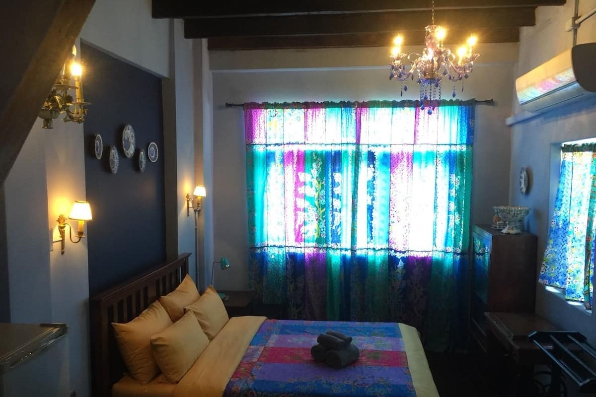 Ein Schlafzimmer mit Bett, einer Kristallleuchter, einem Fenster mit bunten Vorhängen und Wandlampen.