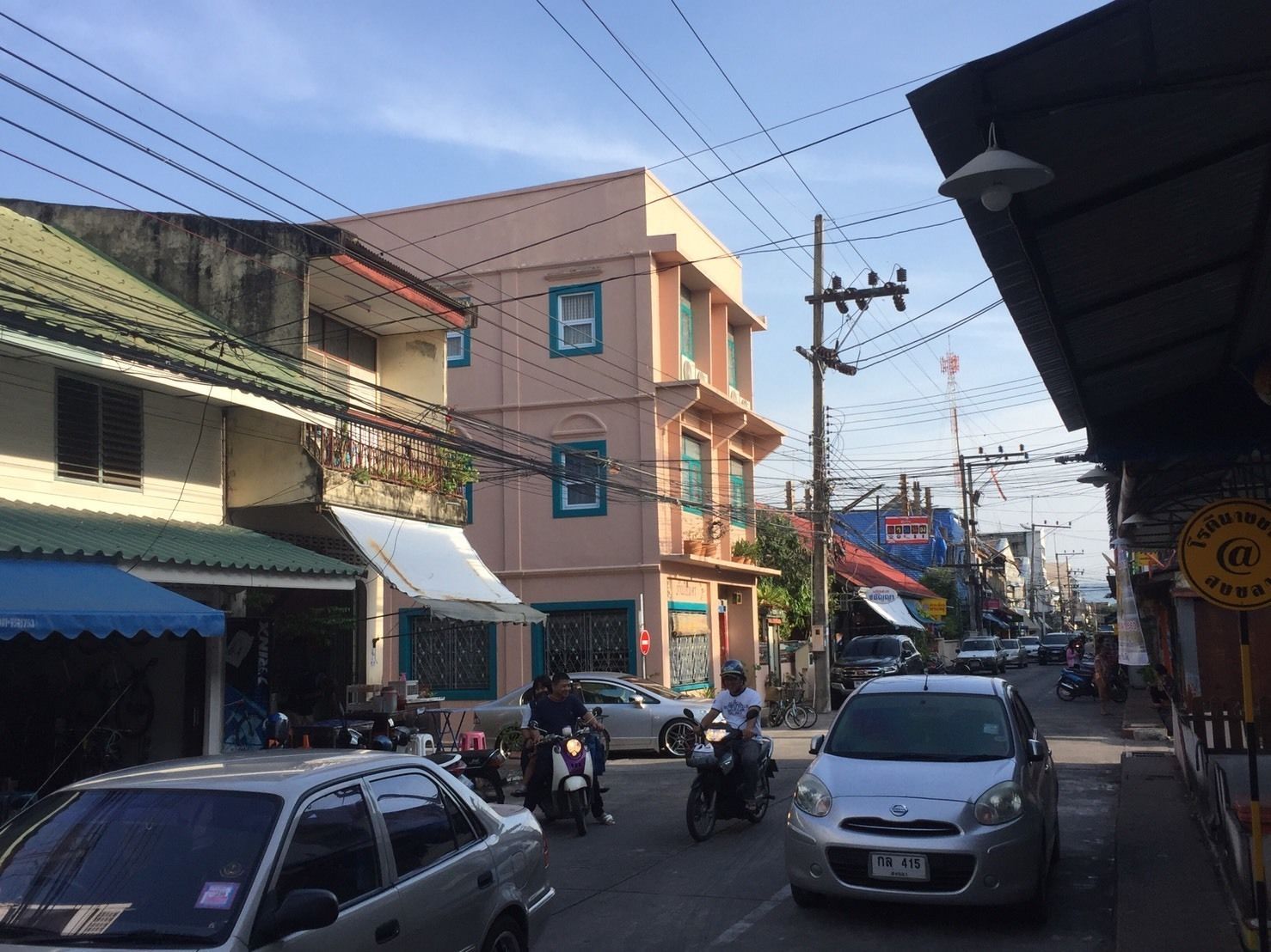 A street scene with buildings, parked cars, and motorcycles.