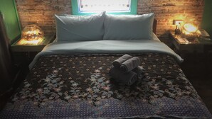 Ein Bett mit einer blumigen Bettdecke, zwei Kissen und einem Stapel Handtücher.