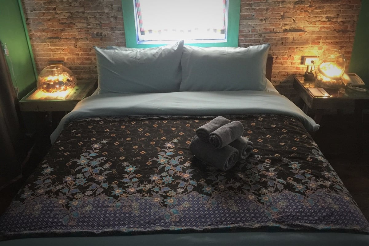 Ein Bett mit einer blumigen Bettdecke, zwei Kissen und einem Stapel Handtücher.